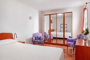 Une chambre d’hôtel comprenant un lit, deux chaises, un bureau, un miroir et une armoire.