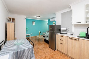 Eine kompakte Küche mit Kühlschrank, Spüle und einer Essecke mit Tisch und Stühlen.