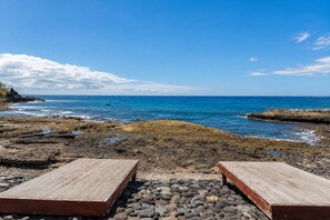 A rocky beach with two wooden benches facing the ocean.