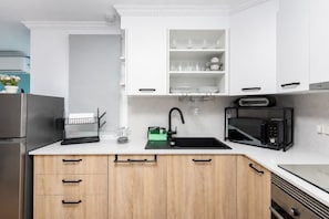 A modern kitchen with white cabinets, a black sink, a microwave, and a built-in oven. - GuestReady - Mis tres sentidos near the Beach (Arinaga)