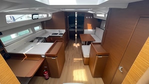 A compact galley with a stove, sink, and storage cabinets. There is a small seating area with a table and cushioned seats. - Sun-Kissed Sailing Adventure in Islas Baleares, Mallorca (Palma)