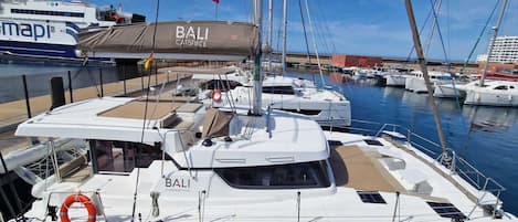 A marina with multiple boats, including a prominent white yacht named 'BALI' with 'CATANASTROUD' written on the side.