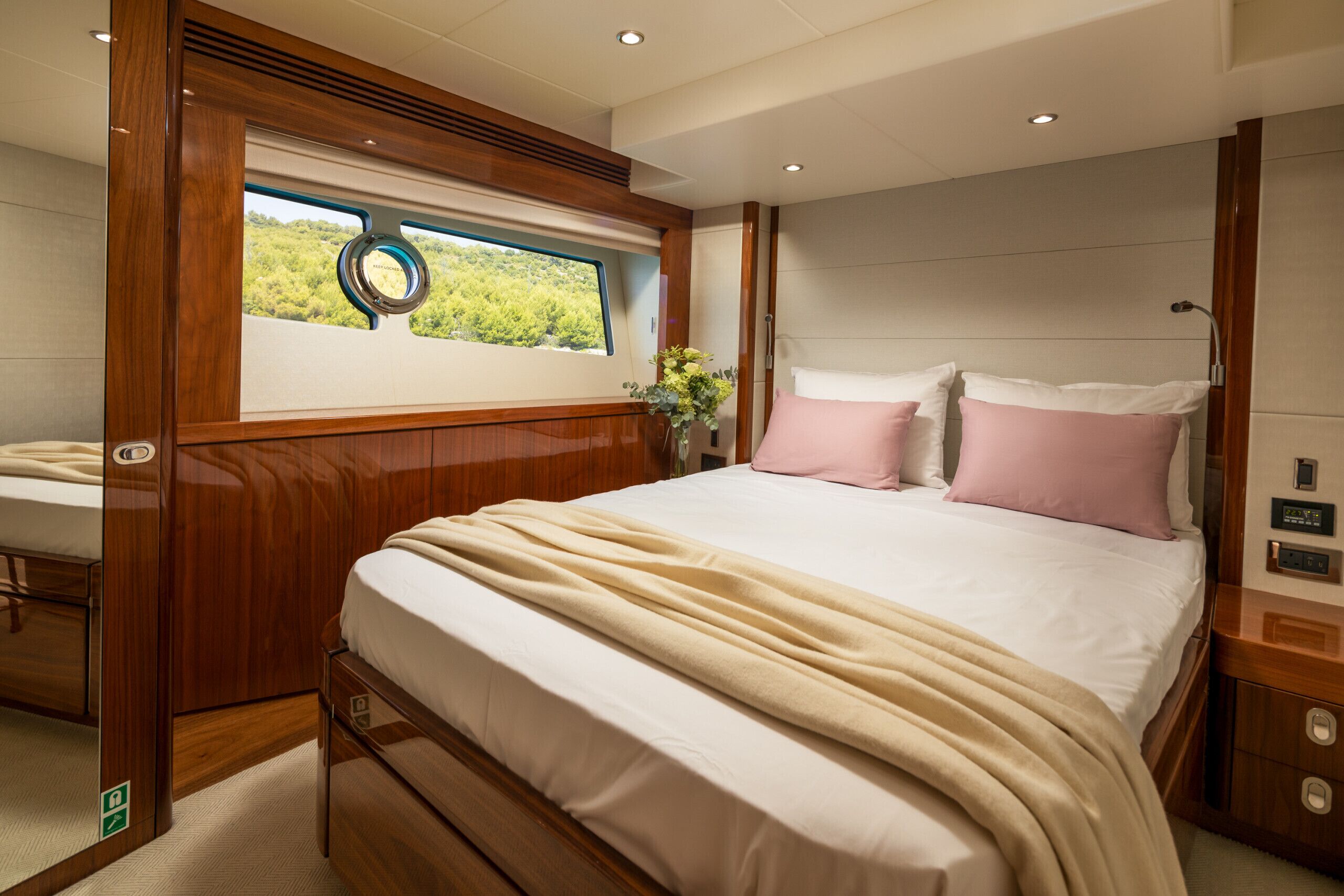 A bedroom with a bed, a window with a view, a bedside table, and a nightstand.