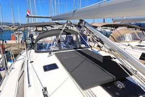 A sailboat docked at a marina with multiple masts in the background, a covered deck area, and a small window. - Sun-Kissed Sailing Adventure in Zadar, Croatia (Biograd na moru)