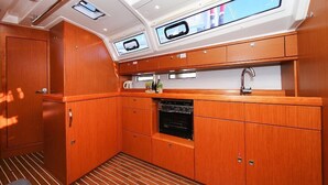 A compact kitchen with wooden cabinets, a built-in oven, and a window with a view. - Sun-Kissed Sailing Adventure in Istria, Croatia (Pula)