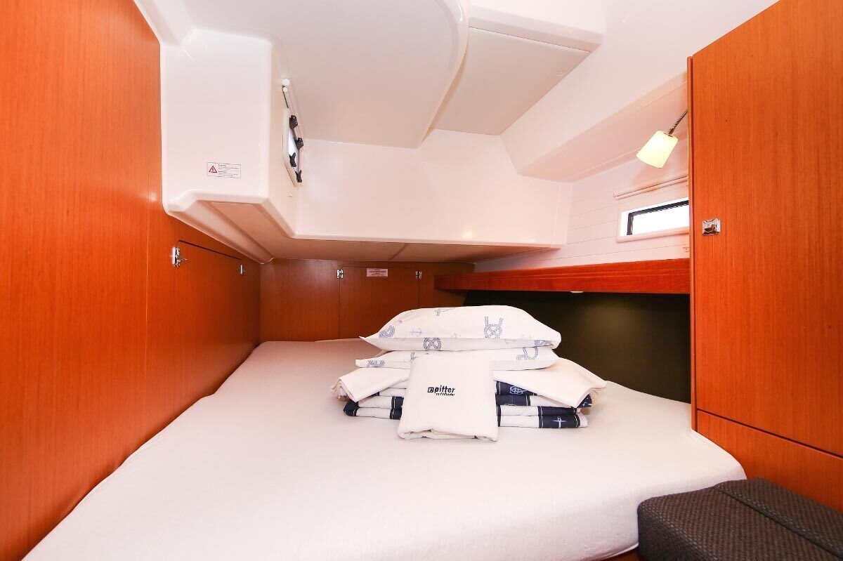 Une petite cabine équipée d’un lit superposé, d’une petite table et d’un banc.