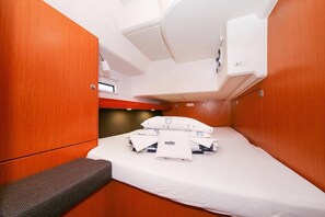 Een kleine kamer met een bed, een klein bankje en een raam.
