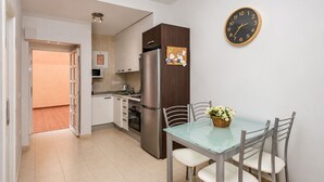 Una cocina moderna con un refrigerador de acero inoxidable, una mesa de comedor con sillas y un reloj de pared.