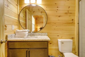 Ein Badezimmer einer Holzhütte mit Waschbecken, Spiegel und Toilette.