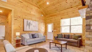 A log cabin interior with a sofa, armchair, coffee table, and a painting on the wall. - Dolly's Cabin: Walk to Dollywood Private Spa View (Pigeon Forge)
