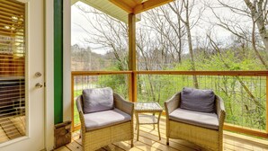A covered porch with wicker furniture and a door. - Dolly's Cabin: Walk to Dollywood Private Spa View (Pigeon Forge)