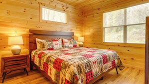 A wooden cabin bedroom with a bed, two bedside tables, and a window. - Dolly's Cabin: Walk to Dollywood Private Spa View (Pigeon Forge)