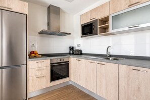 Een moderne keuken met een roestvrijstalen koelkast, een inbouwoven, een magnetron en een koffiezetapparaat.