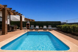 A rectangular swimming pool with a wooden pergola on one side, lounge chairs, and a barbecue grill. - GuestReady - Luxury Villa with Private Pool (Antigua)