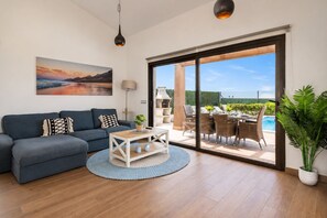 A modern living room with a sofa, coffee table, and a painting on the wall. - GuestReady - Luxury Villa with Private Pool (Antigua)