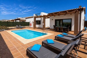 Ein Pool mit Liegestühlen und einer überdachten Terrasse.