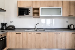 A modern kitchen with wooden cabinets, a stainless steel sink, a microwave, a toaster, and a coffee maker. - GuestReady - Luxury Villa with Private Pool (Antigua)