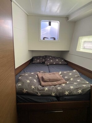 Ein kleines Schlafzimmer mit einem Einzelbett, einem Fenster und einer kleinen Deckenleuchte.