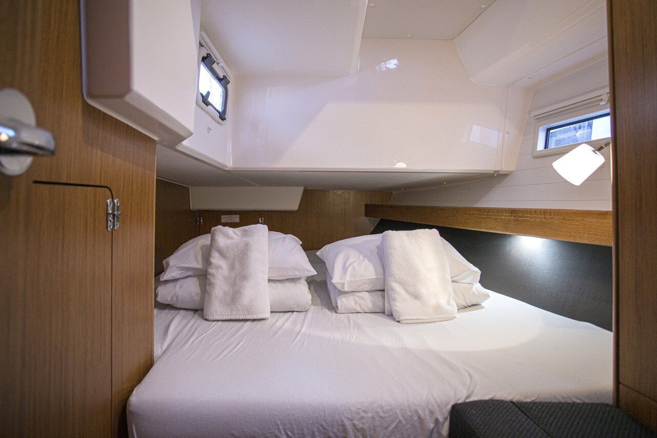 Una cabina compatta e ben illuminata con un letto, cuscini e una testiera.