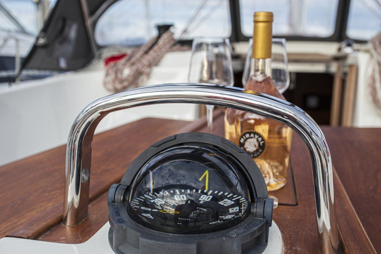 A steering wheel with a speedometer, a bottle of liquor, and a rope on a boat deck.