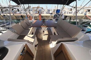 A boat deck with a central table, cushioned seating, and a steering wheel. - Sun-kissed Sailing Adventure in Split-Dalmatia, Croatia (Trogir)