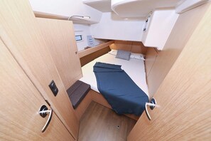 Kompakti, hyvin valaistu ohjaamo, jossa on kerrossänky, pieni oleskelualue ja ohjauspaneeli.