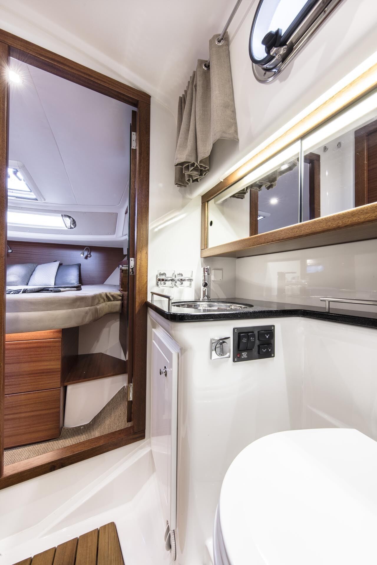 Une salle de bain moderne et compacte, avec un lavabo blanc, un miroir et une petite fenêtre.
