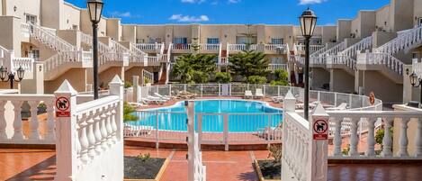 A hotel pool area with a clear blue pool, white railings, and a no-trader sign.