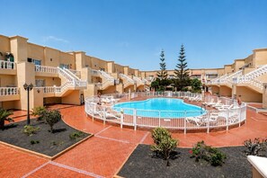 Ein Poolbereich mit einem runden Pool, umgeben von einem weißen Zaun, und mehreren Balkonen mit Geländern.