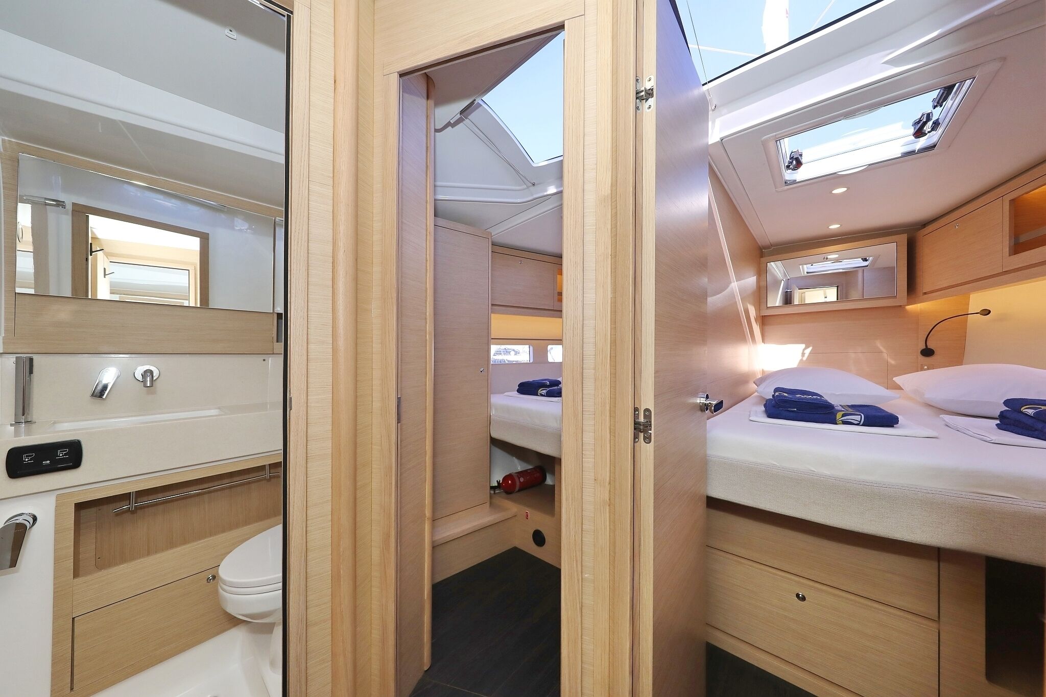 Ein kleines, modernes Badezimmer mit Toilette, Waschbecken und Duschbereich, sowie ein Schlafzimmer mit Bett, Nachttisch und einem Oberlicht.