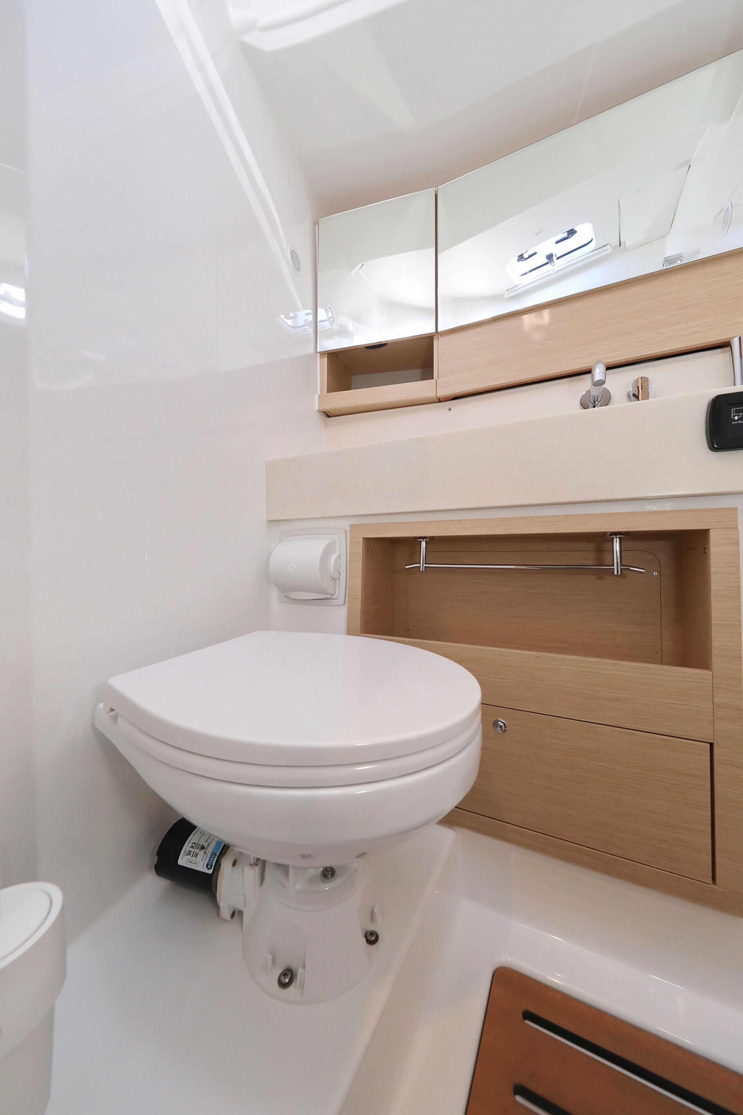 Une salle de bain moderne avec des toilettes blanches, un meuble-lavabo en bois et un miroir au-dessus du lavabo.