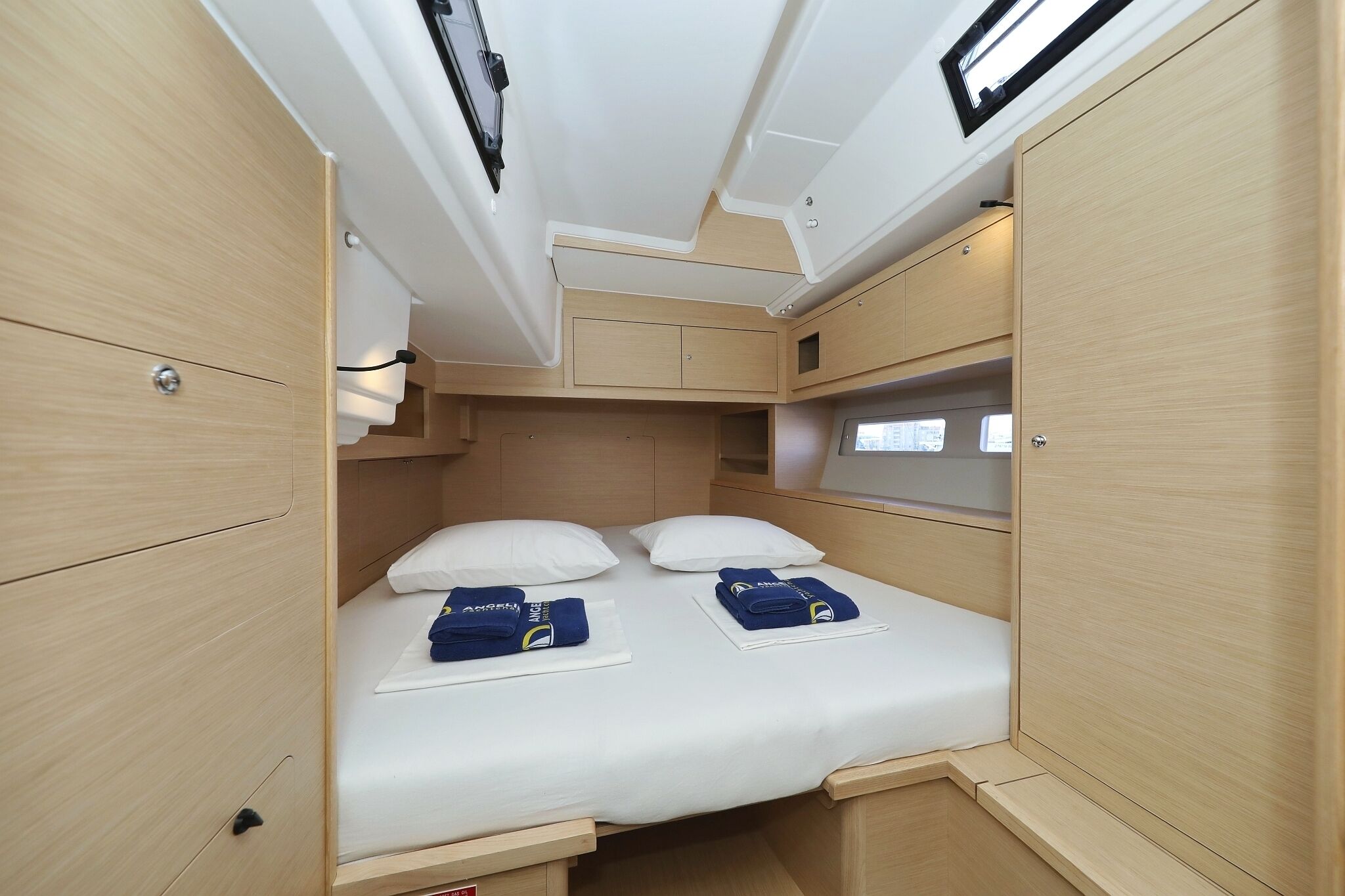 Un interior pequeño y bien iluminado con una cama, armarios de almacenamiento y un ventanal.