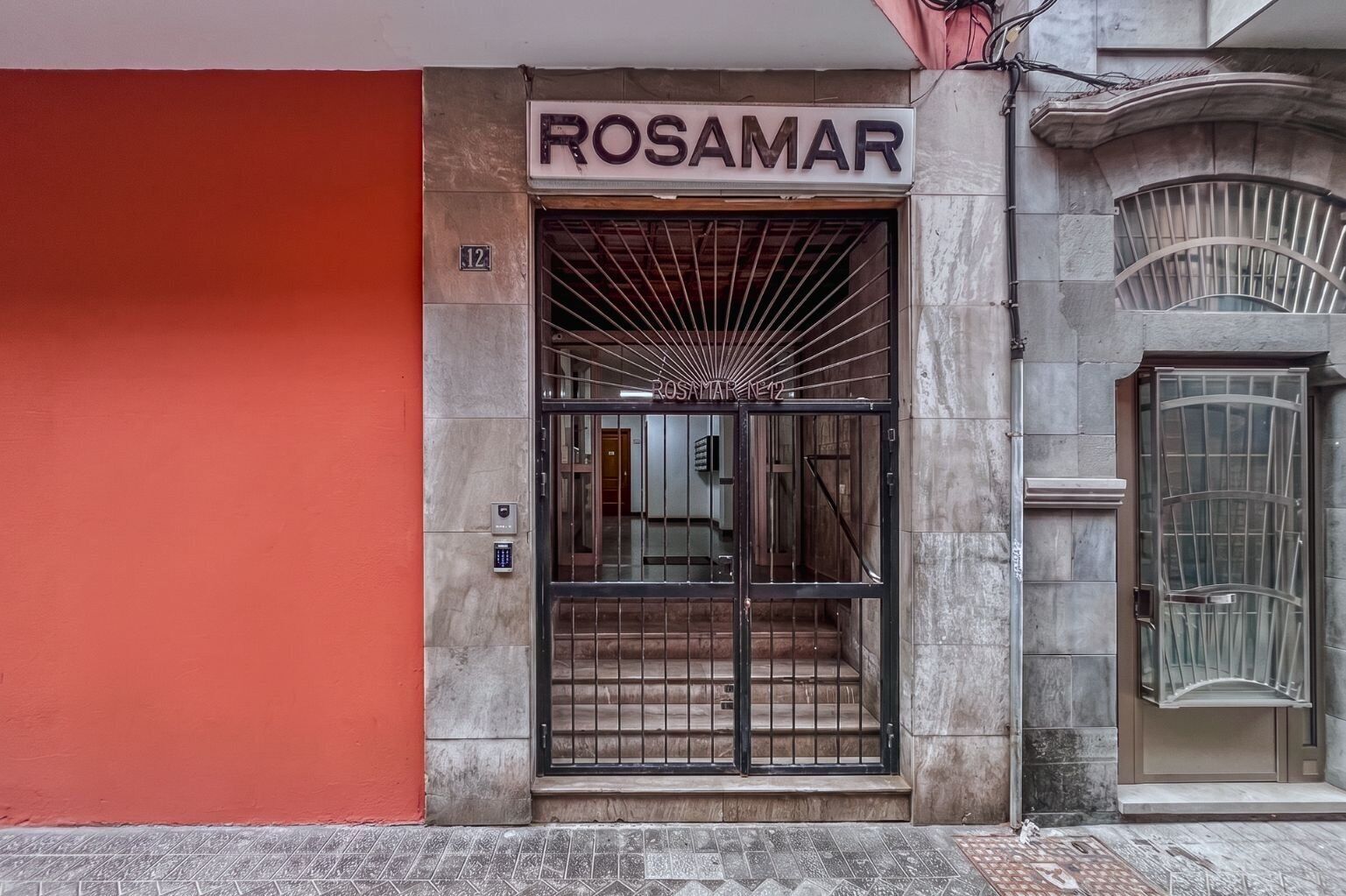 Entrada de un edificio con un letrero que dice 'ROSAMAR' y el número '12' sobre la puerta.