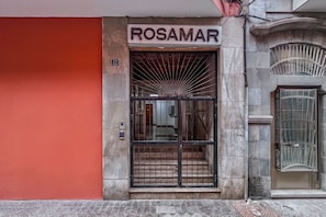 A building entrance with a sign reading 'ROSAMAR' and a number '12' above the door. - GuestReady - Rosamar 104 M (Las Palmas de Gran Canaria)