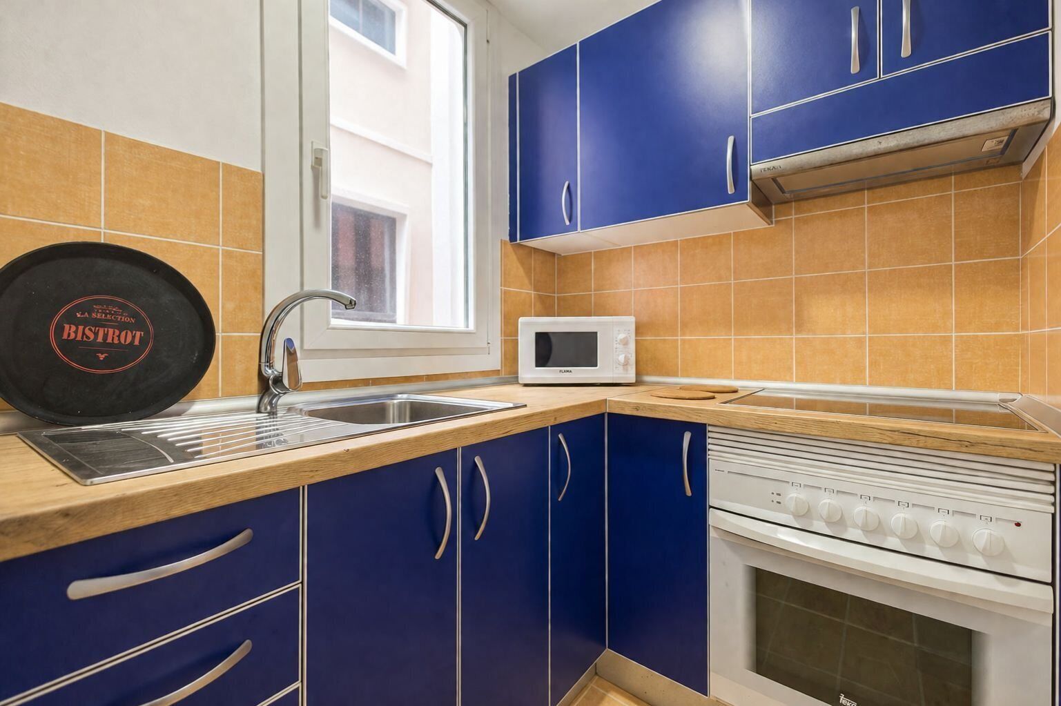 A kitchen with blue cabinets, a white microwave, and a stove.