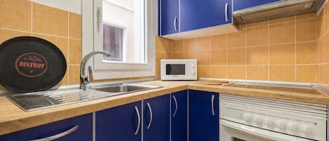 A kitchen with blue cabinets, a white microwave, and a stove.