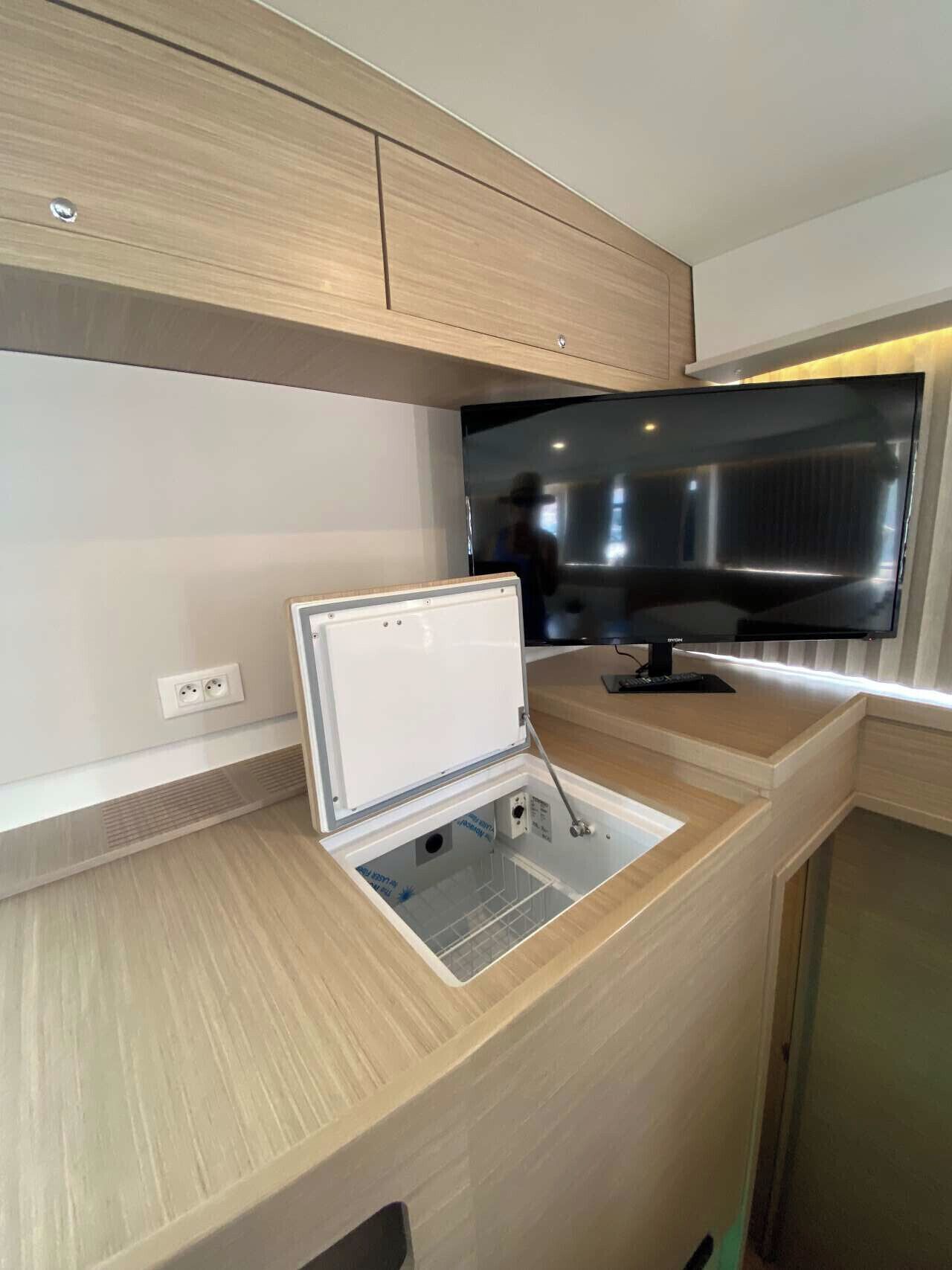 A modern kitchen with a built-in laptop, a flat-screen TV, and a power outlet.