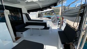 A boat deck with seating areas, a table, and a rope coiled on the side. - Sun-kissed Sailing Adventure in Split-Dalmatia, Croatia (Trogir)
