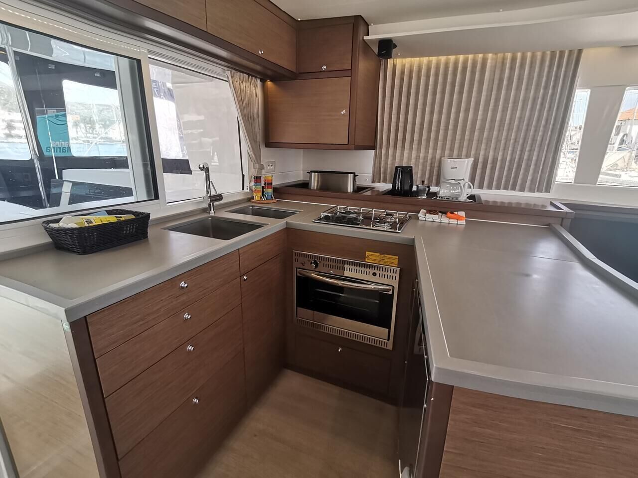 Cocina compacta con horno integrado, lavamanos y ventana con cortinas.