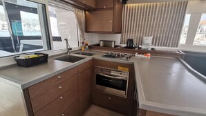 Eine kompakte Küche mit Backofen, Spüle und einem Fenster mit Vorhängen.