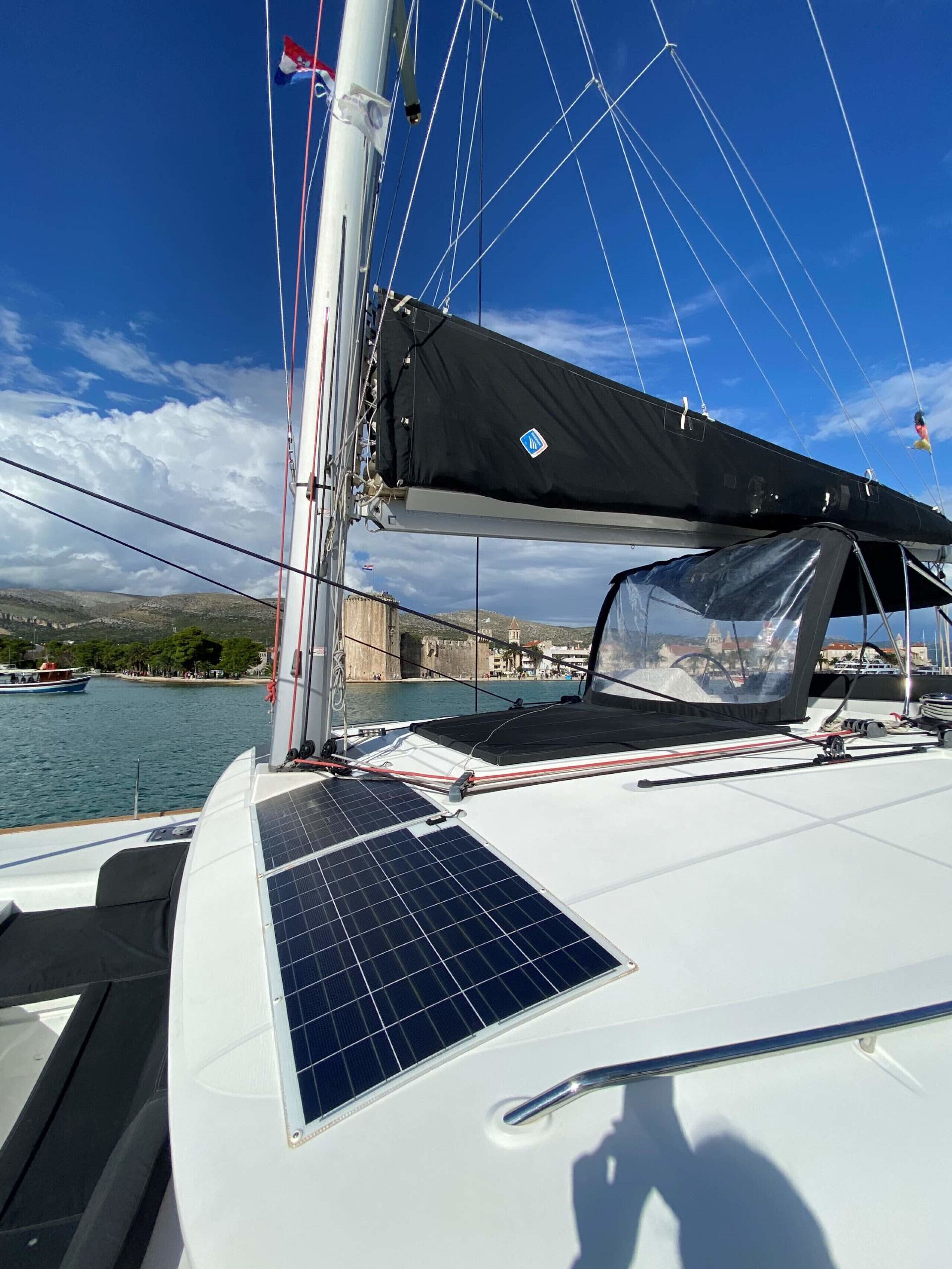 A sailboat with a black canopy, solar panels, and a view of a coastal town.