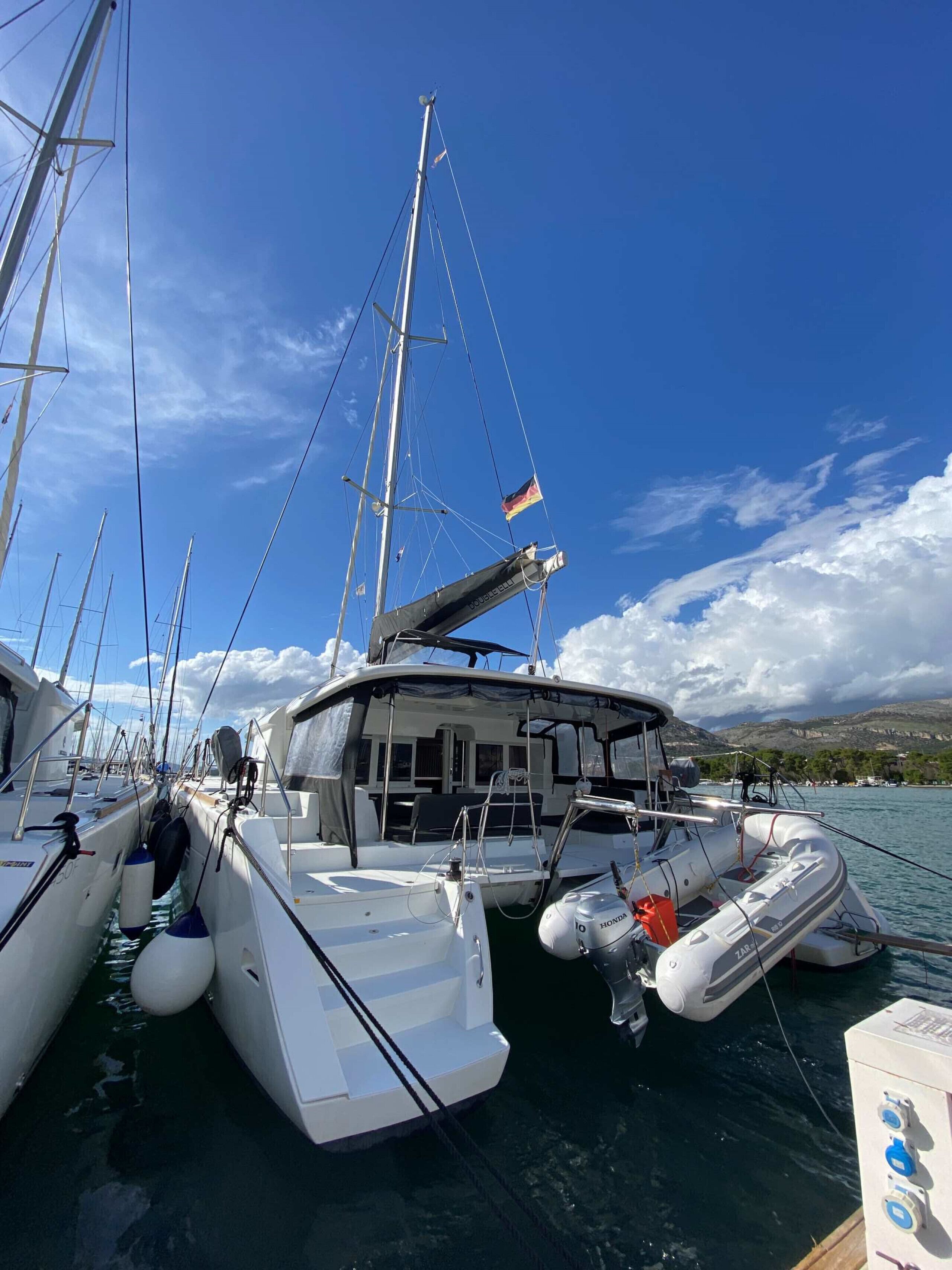 A marina with several sailboats docked, featuring masts, sails, and flags.