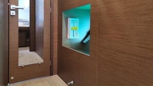 Eine Holzwand mit einem Spiegel, einem Lichtschalter und einem kleinen Regal mit einer Schachtel.