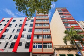 Ein mehrstöckiges Gebäude mit moderner Architektur, das rote, weiße und beige Farbtöne kombiniert.