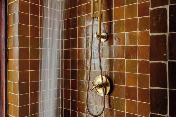Una ducha con cabezal de ducha de mano y mandos en la pared.