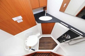 Ein kleines Badezimmer mit Waschbecken, Holdekor-Schränken und einer Duschkabine.