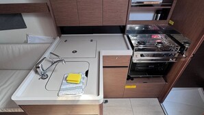 Une petite cuisine équipée comprenant un évier, une cuisinière et des placards de rangement.