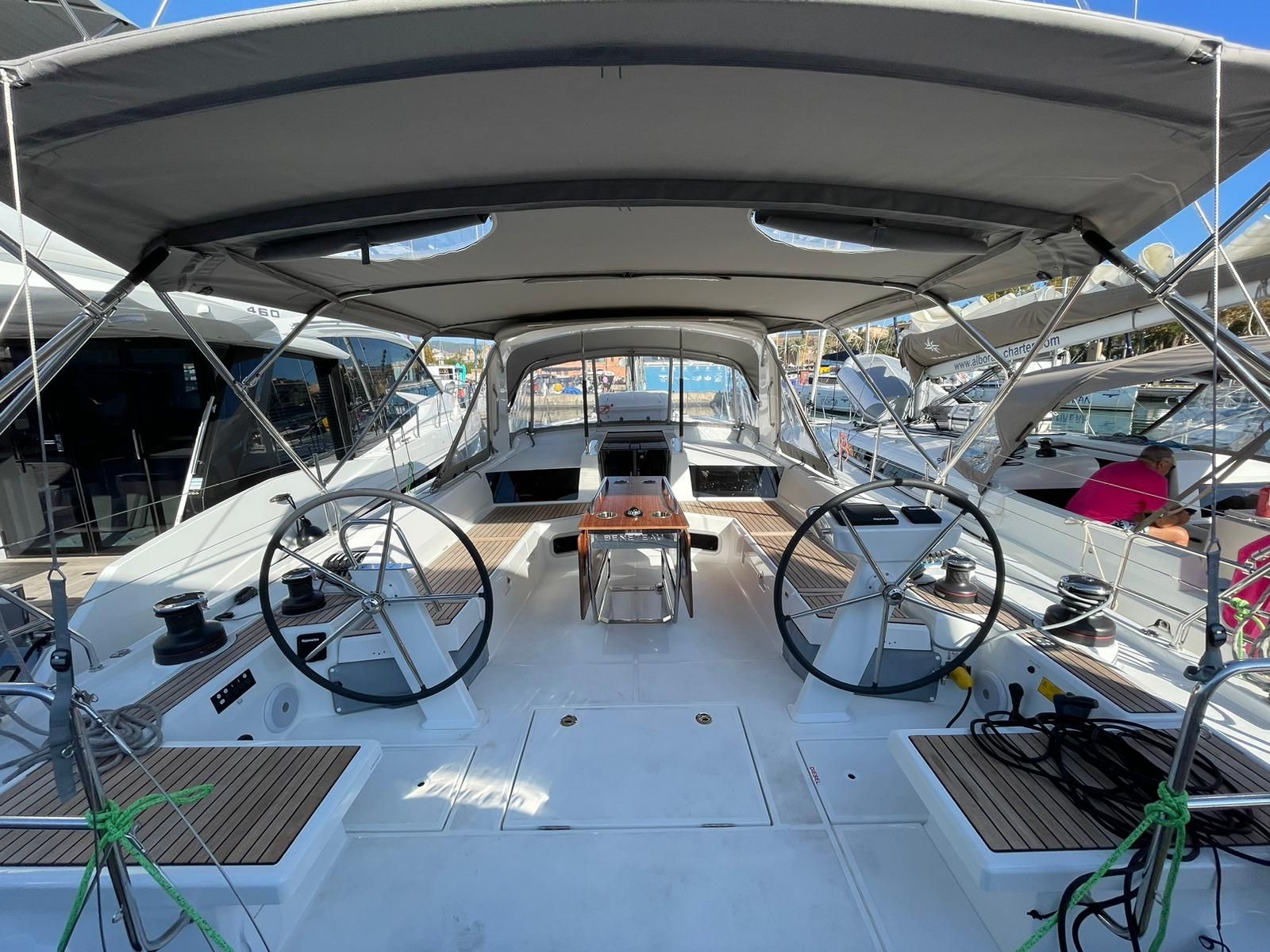 Cubierta de barco con una mesa central, timón y zona de estar.