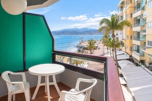 Ein Balkon mit Meerblick, zwei weiße Plastikstühle und ein kleiner runder Tisch.