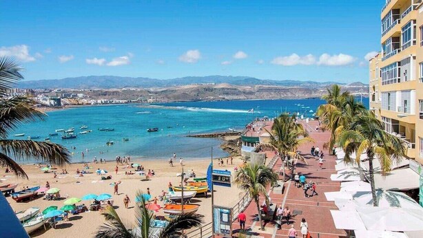 A coastal view with a beach, boats, and a building with balconies. - GuestReady - DiMar Sea View Premium (Las Palmas de Gran Canaria)